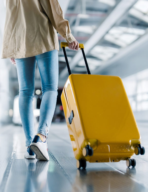 Woman pulling yellow suitcase in airport.