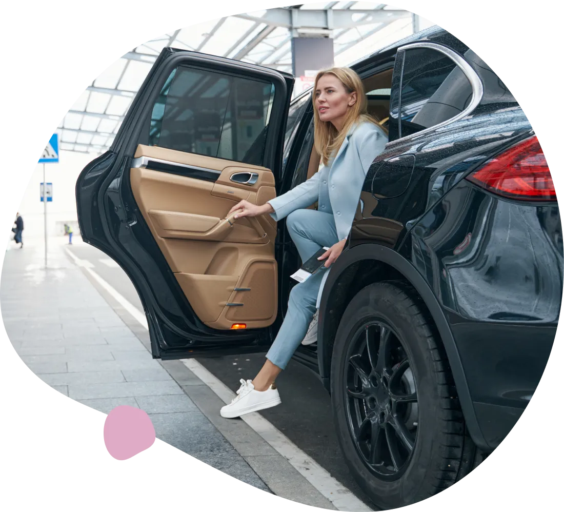 Woman exiting luxury car; airport arrival.