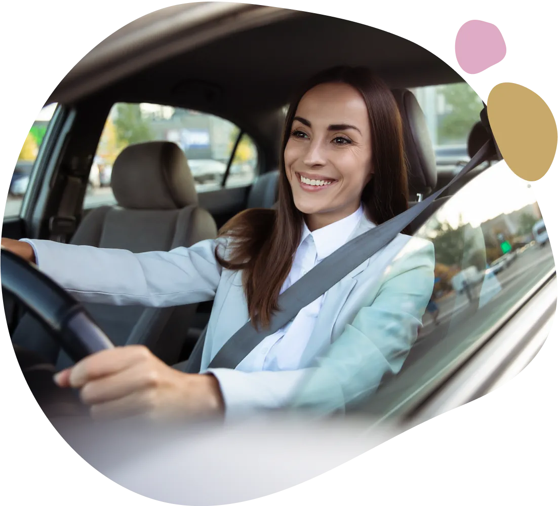 Here's an alt tag for the image: Smiling woman driving car.