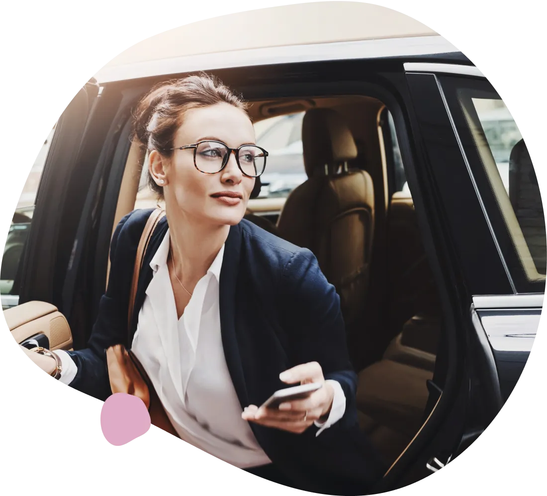 Businesswoman exiting black car, phone in hand.